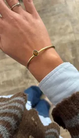 Pulsera rígida dorada con piedra ojo de tigre ovalada engarzada.