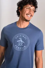 Remera de cuello redondo y manga corta, color azul, con estampado circular en el pecho que incluye el logo de la marca Original Penguin.
