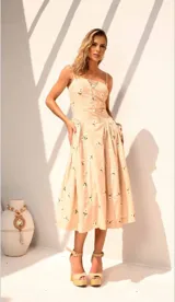 Vestido midi color beige con estampado de flores blancas, breteles finos y escote con cordones.