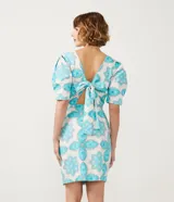 Vestido corto blanco con estampado de flores y corazones en color celeste, de corte recto, con mangas abullonadas y lazo en la espalda.