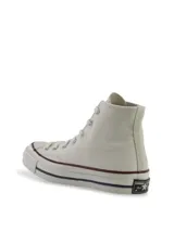 Zapatillas Converse Chuck 70 de caña alta color crema, confeccionadas en lona premium con costuras reforzadas, puntera y vira laqueada con trama de diamante, parche de cuero en el tobillo, cordones de algodón y ojalillos cromados.