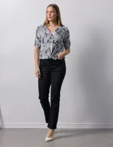 Blusa celeste con estampado blanco, de gasa, con cuello a la base y escote en V. Tiene abertura con botones, bolsillos delanteros y mangas 3/4 regulables con presilla y botón. El ruedo termina con un nudo.