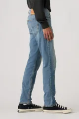 Jean de corte slim fit, color celeste, con cierre de cremallera y botón metálico. Presenta un diseño clásico de cinco bolsillos con costuras reforzadas.