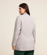 Blazer de corte sastrero color gris claro, con solapas, abotonado doble, forro interno y bolsillos frontales decorativos con solapa.