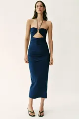 Vestido midi de color azul marino con escote halter y tirantes finos ajustables. Presenta un diseño con drapeados frontales y laterales, detalle cut out en el pecho con fornituras metálicas doradas y falda de corte evasé.