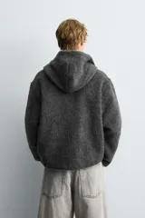 Sobrecamisa de corte relajado confeccionada en tejido con textura efecto pelo. Presenta cuello con capucha, manga larga, bolsillos laterales y cierre frontal con cremallera.