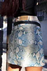 Minifalda con estampado de piel de serpiente en tonos celeste y blanco, con pretina ancha color crudo y cinturón fino negro.