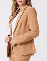Blazer sastrero entallado color beige, con cuello de solapa, cierre frontal con un botón a tono y hombreras estructuradas. Presenta bolsillos laterales con solapa y forro interno.
