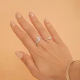 Set de dos anillos de plata 925 con engaste de circonias. Uno de los anillos presenta un diseño solitario con una piedra central, mientras que el otro tiene una forma en V con piedras pequeñas incrustadas.