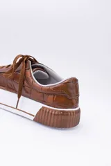 Zapatillas bajas color dorado con diseño trenzado, cordones y suela de goma.