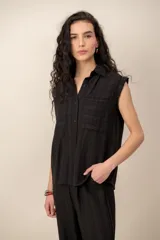 Conjunto compuesto por una blusa sin mangas con cuello camisero, bolsillos frontales y cierre de botones, y un pantalón largo de corte recto y holgado, ambos confeccionados en tejido texturizado de color marrón.