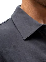 Camisa de lino azul marino de manga larga, con cuello clásico y cierre frontal con botones.