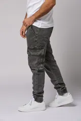 Pantalón jean gris oscuro de corte jogger con bolsillos cargo laterales y puños elásticos en los tobillos.