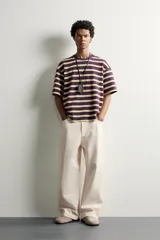 Camiseta de corte relaxed fit con diseño de rayas horizontales en tonos morado, amarillo y blanco. Presenta cuello redondo y mangas cortas.