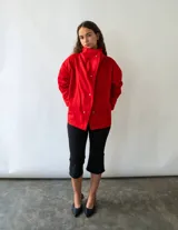Campera de algodón color rojo, con cuello alto, cierre frontal con botones metálicos y diseño versátil de corte holgado.