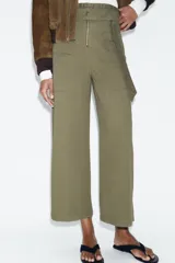Pantalón de tiro alto con diseño paperbag, pernera ancha y cierre frontal con cremallera. Cuenta con bolsillos laterales de plastrón con solapa y cintura con trabillas.