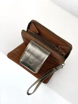Billetera compacta de cuero texturizado color marrón, con solapa frontal en cuero metalizado dorado que presenta un grabado de búho. Incluye cierre lateral y correa de muñeca a juego.