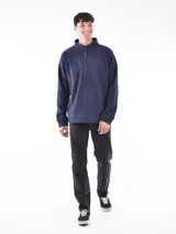 Buzo de polar color verde oliva, con cuello alto y cierre frontal parcial. Presenta puños y cintura acanalados.