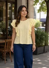 Blusa de broderie color amarillo, sin mangas, con diseño de volados en los hombros y detalles perforados en el tejido.