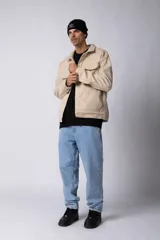 Campera corta tipo sobrecamisa de paño elastizado color beige, con cuello camisero, cierre frontal con botones veteados y dos bolsillos frontales con tapa.