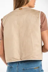 Chaleco sin mangas, color beige claro, con bordados florales en relieve y ribetes a contraste.