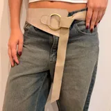 Cinto ancho de cuero marrón con diseño asimétrico, que presenta un aro metálico dorado como elemento central y una tira de gamuza larga que se anuda para el cierre.