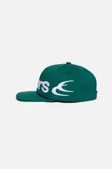 Gorra Scuffers de algodón twill color verde, con diseño estructurado y visera plana. Presenta bordado en relieve del logo en color blanco que envuelve el frente y los laterales.