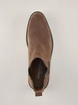 Bota Chelsea de gamuza gris con elásticos laterales, suela de goma marrón y tirador trasero.