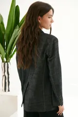 Blazer de mujer color gris oscuro con textura de jean/lino, corte oversize, hombreras, bolsillos frontales y pespuntes a contratono. Cierre frontal con botones.