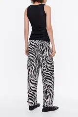 Pantalón de viscosa con estampado animal print, corte recto, largo tobillero, cierre frontal con cremallera de plástico, bolsillos falsos con tapetas laterales y cintura con elástico interior.