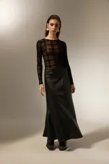 Falda larga de corte evasé confeccionada en cuero sintético negro, con costuras verticales que definen su estructura.
