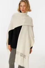 Ruana negra de tejido de punto con flecos y aplique de cuero vacuno con manchas blancas.