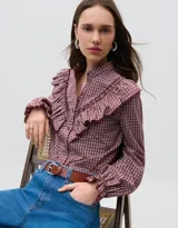 Camisa de manga larga con estampado de cuadros en tonos rojizos, cuello mao y detalle de volados en el frente. Cuenta con cierre frontal de botones y puños con volados.