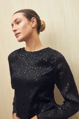 Blusa negra de manga larga con cuello redondo y lentejuelas a tono.