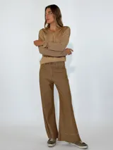 Pantalón marrón acampanado con ruedo desflecado.