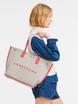 Bolso shopper Longchamp modelo Le Roseau Essential, color crudo con detalles en verde. Presenta logo de la marca en verde y doble asa de hombro.