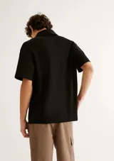 Chomba de manga corta en color beige, con cuello camisero y cierre frontal parcial.