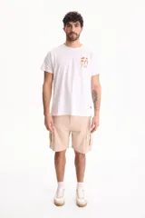 Remera blanca de manga corta y cuello redondo, confeccionada en 100% algodón, con un pequeño estampado minimalista en marrón en el pecho que incluye figuras geométricas, una palmera y olas.