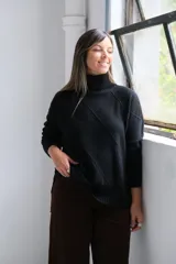 Sweater de punto color negro con cuello alto y diseño de rombos en relieve. Presenta mangas largas con puños acanalados y un corte holgado con aberturas laterales en el ruedo.