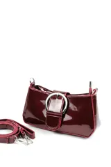 Cartera tipo bandolera de charol rojo, de diseño estructurado, con una hebilla metálica grande decorativa en el frente y correa larga ajustable y desmontable.