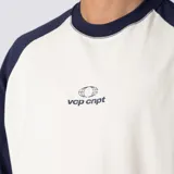 Remera de jersey de algodón con diseño bicolor, cuerpo en color crudo y mangas raglán en azul marino. Presenta escote redondo de ribb y un pequeño estampado gráfico en el centro del pecho.