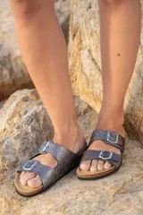 Sandalias de cuero color gris con glitter, con dos tiras anchas ajustables con hebillas metálicas plateadas. Suela anatómica de corcho y goma.