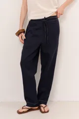 Pantalón de lino azul marino, de corte holgado y silueta recta, con cintura elástica ajustable mediante cordón y detalles de costuras a la vista en contraste.