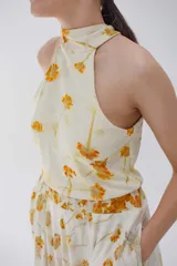 Minivestido color crema con estampado de flores amarillas, cuello halter y falda con volados.