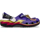 Zuecos Crocs Classic edición especial Yu-Gi-Oh!, de color morado con detalles gráficos de rayos en amarillo y fucsia, correa trasera ajustable y dijes Jibbitz temáticos que incluyen el Rompecabezas del Milenio y una carta de duelo.