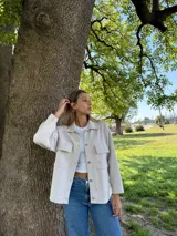 Campera color beige tejida en algodón, de corte recto y manga larga.