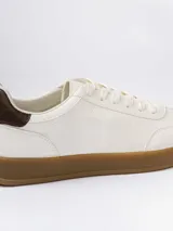 Championes urbanos de diseño minimalista en color blanco, con detalle de talón en color marrón oscuro y suela de goma color caramelo.