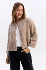 Saco de punto con textura tipo bouclé, de calce relajado y diseño levemente cropped. Cuenta con cuello redondo y cierre frontal mediante botones.