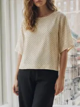 Blusa de manga corta con escote redondo, color crudo con estampado de pequeños puntos marrones.