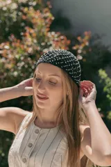 Gorro tejido a crochet color crema con monedas doradas colgando.